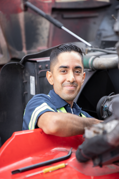 Fleet technician smiles at the camera from the engine he’s working on