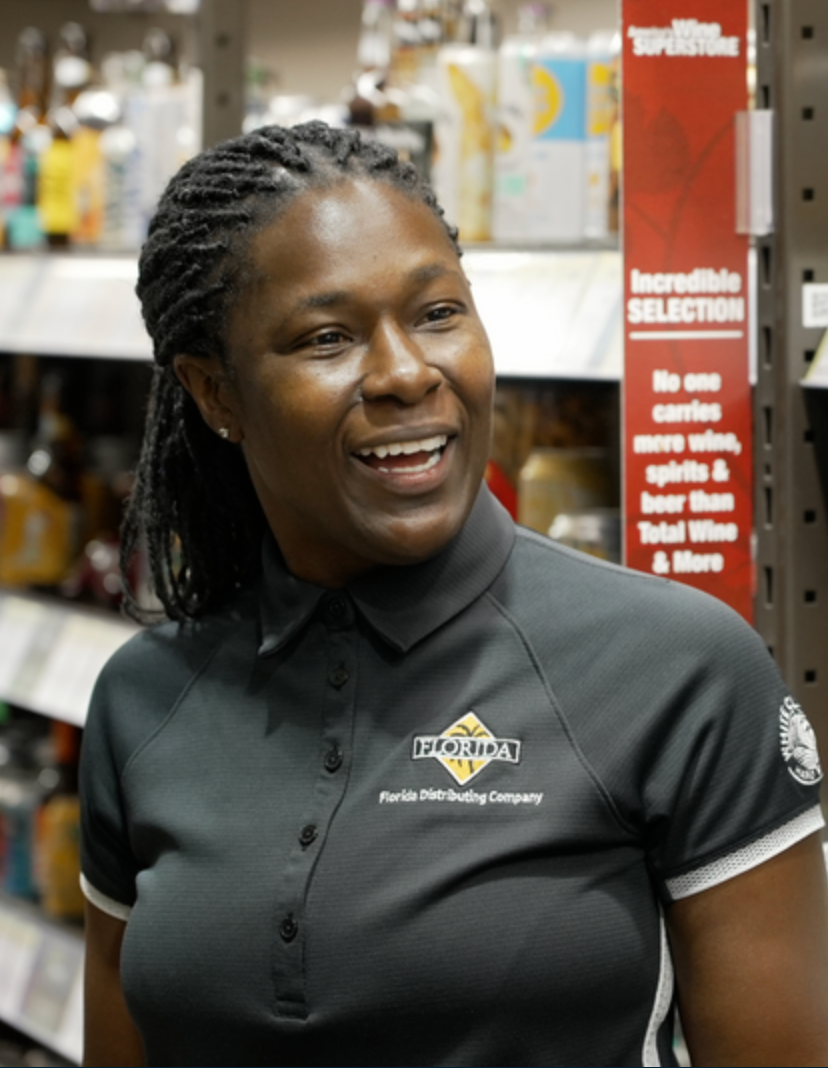 One employee smiling in front of beer products on the shelves