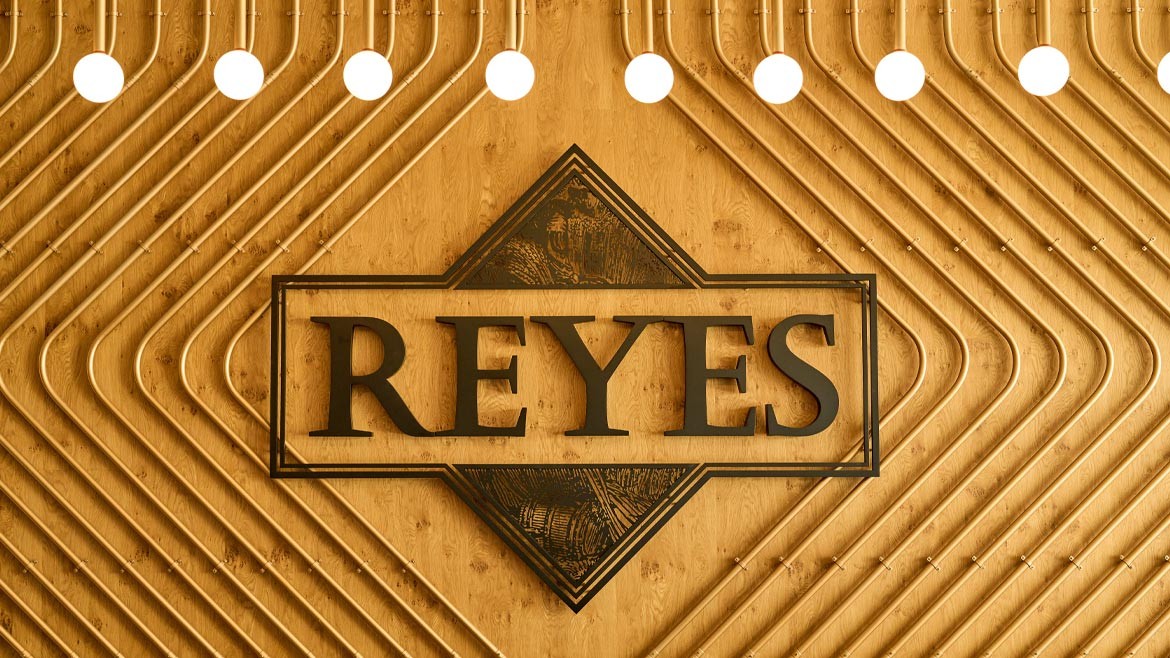 Reyes Beverage Logo on wooden wall.