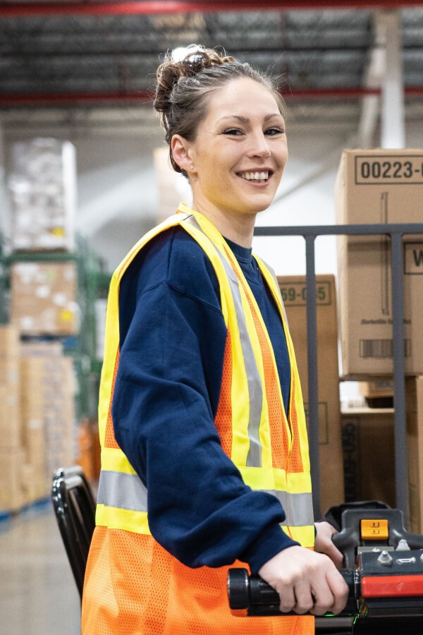 Martin Brower female employee driving an automated pallet jack in warehouse