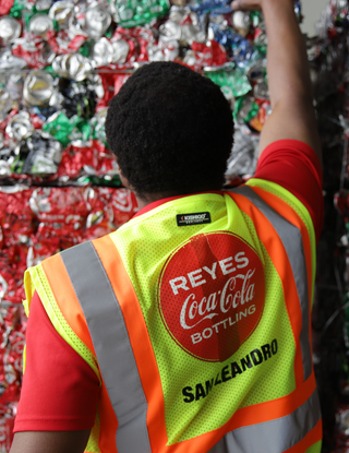 Man in safety vest reaching for pallet of recycled cans